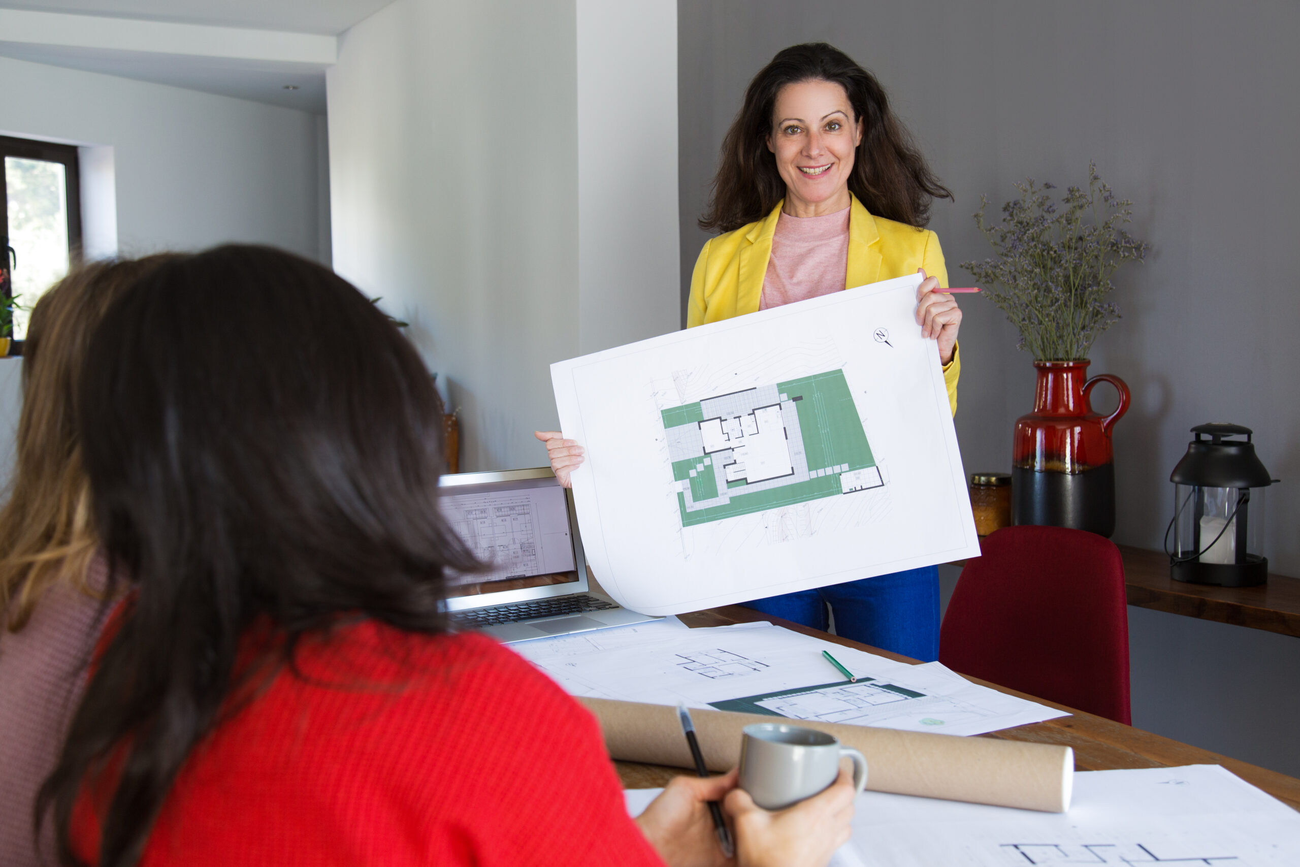 architecte souriant montrant la conception de la maison a des clients ou a des collegues scaled